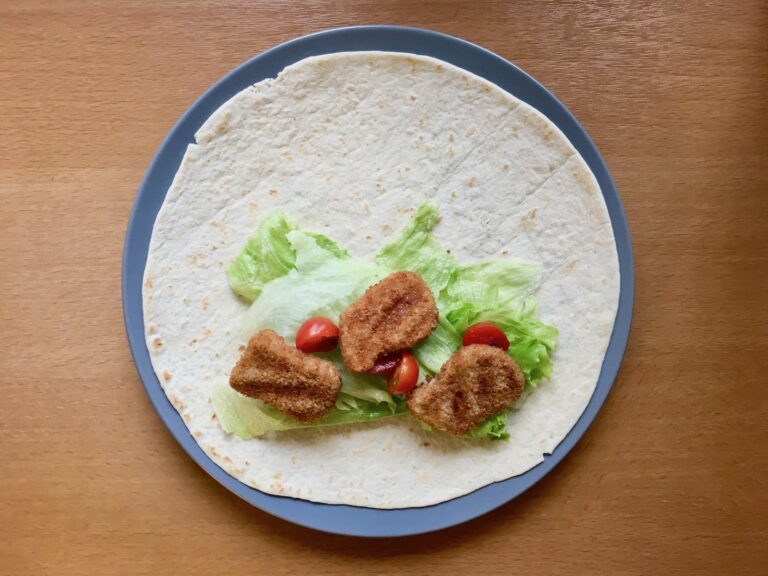 Tortilla mit Salat Tomaten und Chicken Nuggets belegen