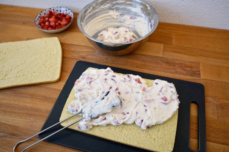 Erdbeer-Sahne-Creme auf Biskuitboden verteilen